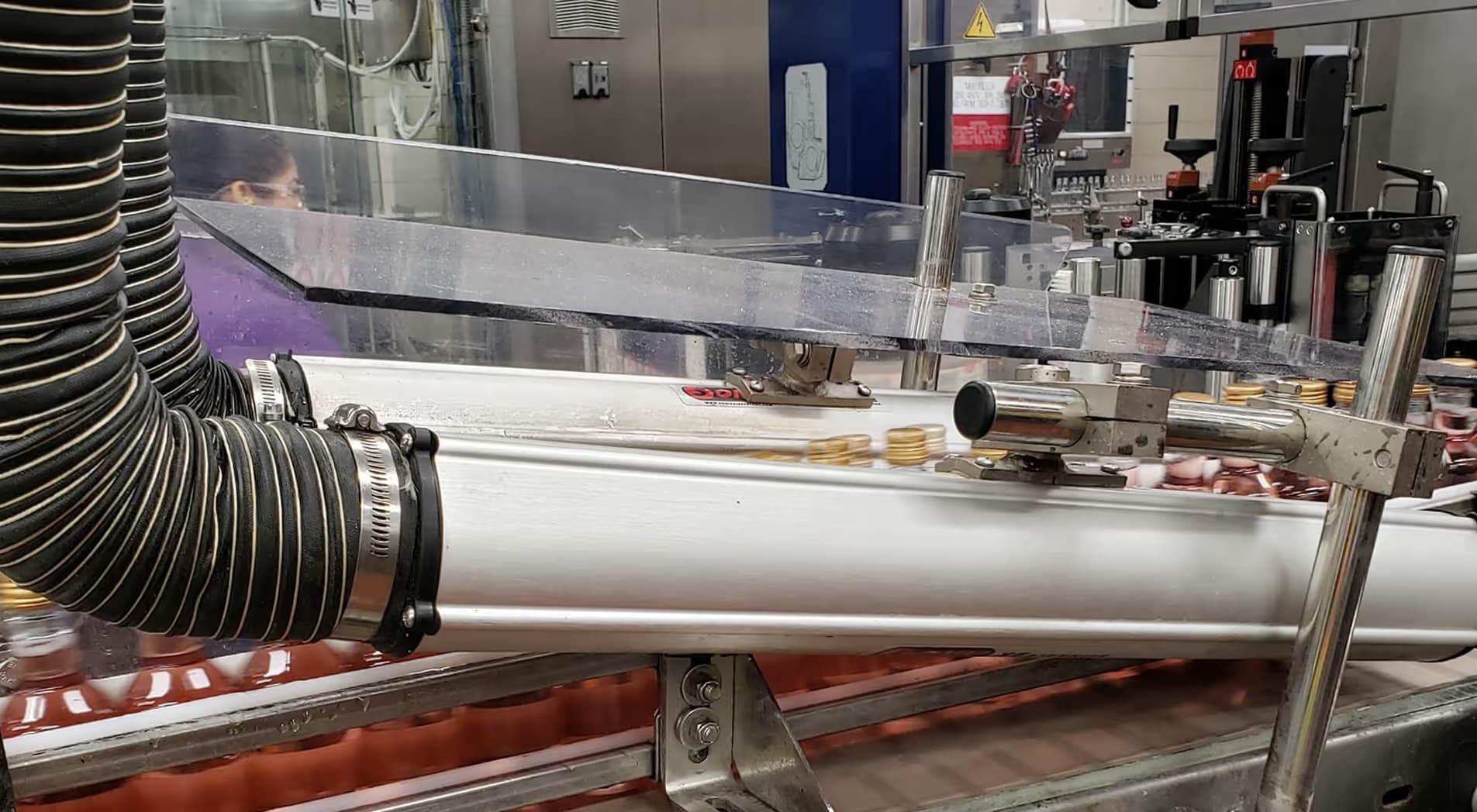 A conveyor belt in a beverage manufacturing facility conveying bottles under a Sonic Air Systems air knife.