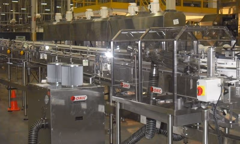 An industrial stainless steel conveyor production line featuring a Sonic Air Systems air knife drying and cleaning station with visible filters and protective clear guards.