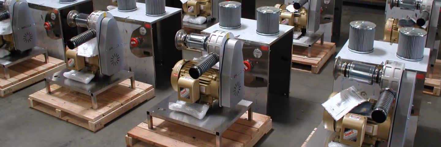 Rows of SuperB industrial centrifugal blowers with gold motors and grey filter housings are positioned on individual wooden pallets on a warehouse floor, ready for shipping.